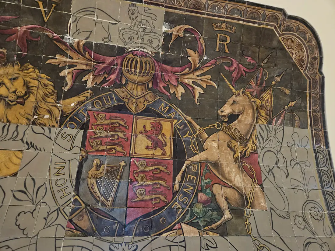 Restored section of a painted tile mural showing the lion, shield and unicorn