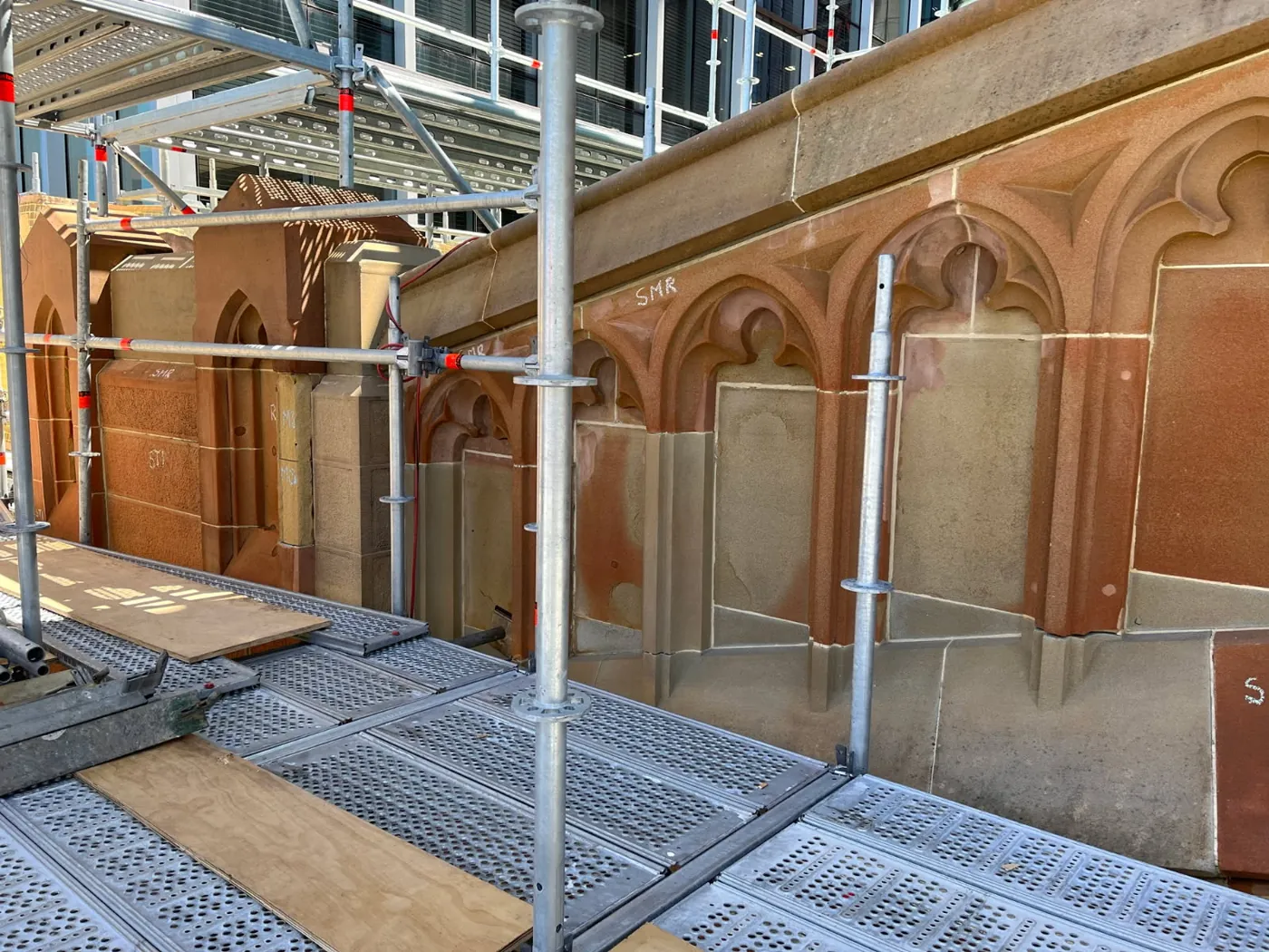 Heritage sandstone tracery and mouldings mid-restoration behind scaffolding